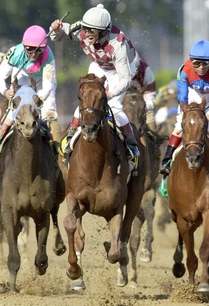 Jockey Jose Santos raised his hand in victory after he rode Funny Cide to a 1-length triumph over Empire Maker, left, in the 129th Kentucky Derby yesterday at Churchill Downs. May 3, 2003