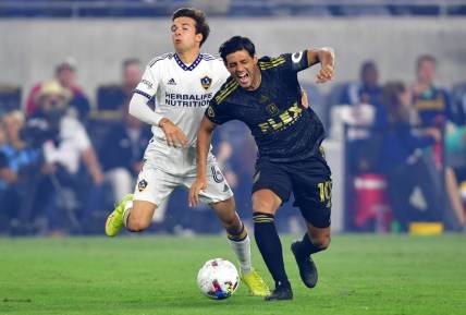Oct 20, 2022; Los Angeles, California, US; Los Angeles Galaxy midfielder Riqui Puig Marti (6) collides with Los Angeles FC forward Carlos Vela (10) during the first half of the MLS Cup Playoff semifinal at Banc Of California Stadium. Mandatory Credit: Gary A. Vasquez-USA TODAY Sports