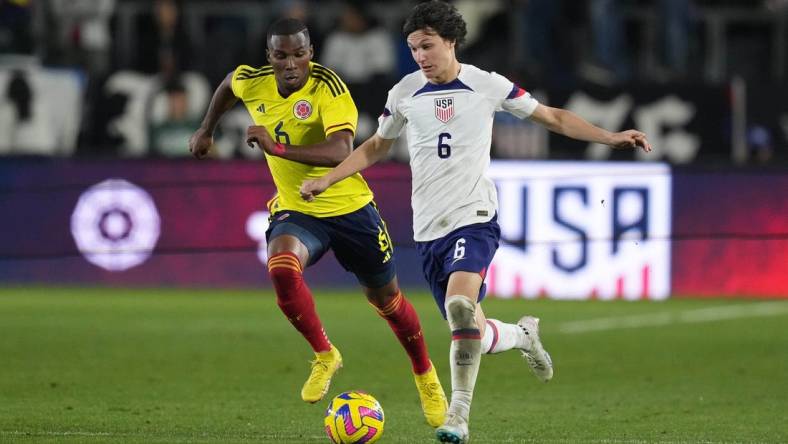 Jan 28, 2023; Carson, California, USA; Columbia defender Juan David Mosquera (left) and USMNT midfielder Paxten Aaronson pursue the ball in the second half at Dignity Health Sports Park. The teams played to a 0-0 tie. Mandatory Credit: Kirby Lee-USA TODAY Sports