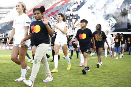Jun 14, 2023; Washington, D.C., USA; Young fans walk with the North Carolina Courage  before ether match against the Washington Spirit at Audi Field. Mandatory Credit: Amber Searls-USA TODAY Sports