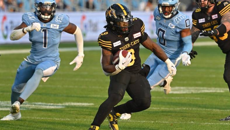 Jun 18, 2023; Toronto, Ontario, CAN;  Hamilton Tiger-Cats quarterback James Butler (9) scores a touchdown past Toronto Argonauts defensive back Robertson Daniel (0) and linebacker Jordan Williams in the second quarter at BMO Field. Mandatory Credit: Dan Hamilton-USA TODAY Sports