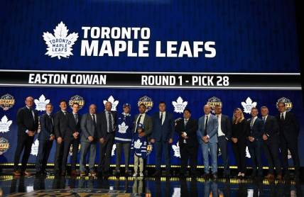 Jun 28, 2023; Nashville, Tennessee, USA; Toronto Maple Leafs draft pick Easton Cowan stands with Leafs staff after being selected with the twenty eighth pick in round one of the 2023 NHL Draft at Bridgestone Arena. Mandatory Credit: Christopher Hanewinckel-USA TODAY Sports