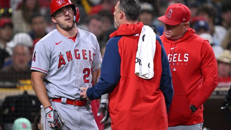 Jul 3, 2023; San Diego, California, USA; Los Angeles Angels center fielder Mike Trout (27) is checked by a trainer after an injury sustained during an at-bat in the eighth inning against the San Diego Padres at Petco Park. Mandatory Credit: Orlando Ramirez-USA TODAY Sports