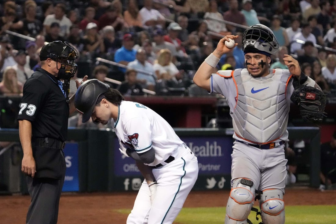 Jul 6, 2023; Phoenix, Arizona, USA; Home plate umpire Tripp Gibson (73) and New York Mets catcher Francisco Alvarez (4) watch as Arizona Diamondbacks left fielder Corbin Carroll (7) tends to an injury during the seventh inning at Chase Field. Mandatory Credit: Joe Camporeale-USA TODAY Sports