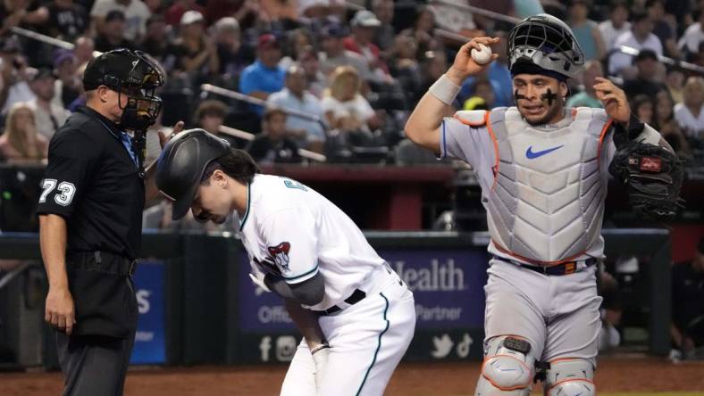 Jul 6, 2023; Phoenix, Arizona, USA; Home plate umpire Tripp Gibson (73) and New York Mets catcher Francisco Alvarez (4) watch as Arizona Diamondbacks left fielder Corbin Carroll (7) tends to an injury during the seventh inning at Chase Field. Mandatory Credit: Joe Camporeale-USA TODAY Sports