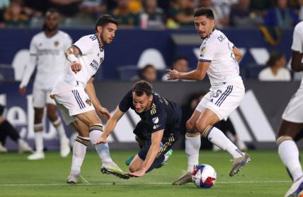 Jul 8, 2023; Carson, California, USA; Philadelphia Union midfielder Deniel Gazdag (10) dribbles against Los Angeles Galaxy midfielder Gaston Brugman (5) and midfielder Marco Delgado (8) during the first half at Dignity Health Sports Park. Mandatory Credit: Jason Parkhurst-USA TODAY Sports