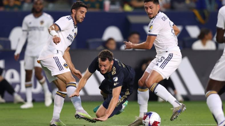 Jul 8, 2023; Carson, California, USA; Philadelphia Union midfielder Deniel Gazdag (10) dribbles against Los Angeles Galaxy midfielder Gaston Brugman (5) and midfielder Marco Delgado (8) during the first half at Dignity Health Sports Park. Mandatory Credit: Jason Parkhurst-USA TODAY Sports