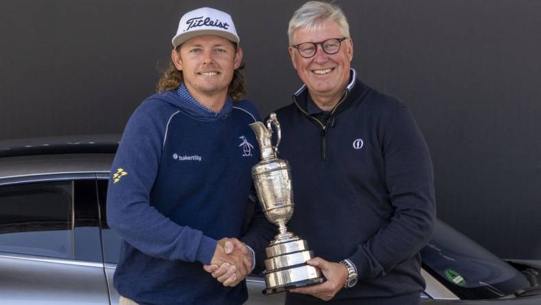 July 17, 2023; Hoylake, ENGLAND, GBR; 2022 winner Cameron Smith (left) arrives with the Claret Jug Trophy and poses with R&A chief executive Martin Slumbers (right) during a practice round of The Open Championship golf tournament at Royal Liverpool. Mandatory Credit: Kyle Terada-USA TODAY Sports