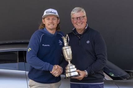 July 17, 2023; Hoylake, ENGLAND, GBR; 2022 winner Cameron Smith (left) arrives with the Claret Jug Trophy and poses with R&A chief executive Martin Slumbers (right) during a practice round of The Open Championship golf tournament at Royal Liverpool. Mandatory Credit: Kyle Terada-USA TODAY Sports