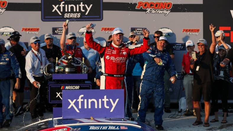 Jul 22, 2023; Long Pond, Pennsylvania, USA; NASCAR Xfinity Series driver Austin Hill celebrates in victory lane after winning the Explore The Pocono Mountains 225 at Pocono Raceway. Mandatory Credit: Matthew O'Haren-USA TODAY Sports