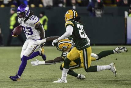 Jan 2, 2022; Green Bay, Wisconsin, USA; Minnesota Vikings running back Dalvin Cook (33) tries to break a tackle by Green Bay Packers linebacker Krys Barnes (51) in the first quarter at Lambeau Field. Mandatory Credit: Benny Sieu-USA TODAY Sports