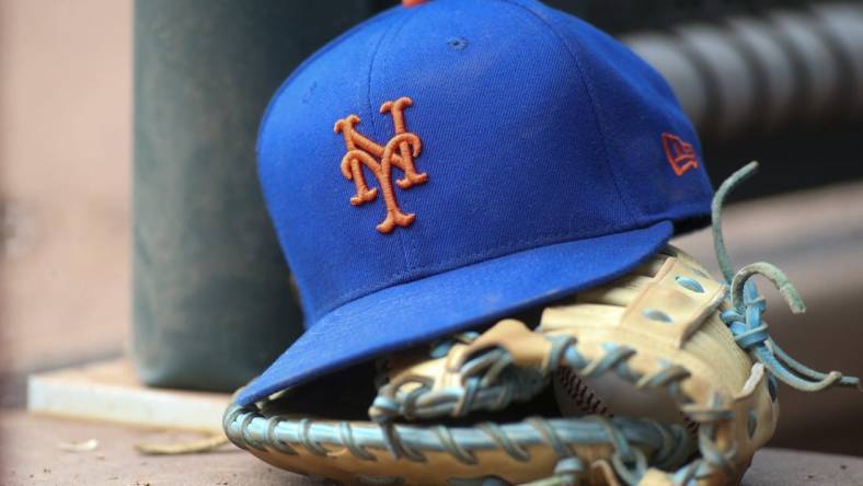 Jul 13, 2022; Atlanta, Georgia, USA; A detailed view of a New York Mets hat and glove in the dugout against the Atlanta Braves in the eighth inning at Truist Park. Mandatory Credit: Brett Davis-USA TODAY Sports