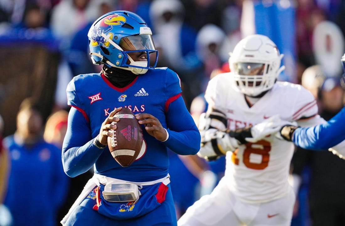 Nov 19, 2022; Lawrence, Kansas, USA; Kansas Jayhawks quarterback Jalon Daniels (6) drops back to pass as Texas Longhorns defensive end Ovie Oghoufo (18) defends during the first half at David Booth Kansas Memorial Stadium. Mandatory Credit: Jay Biggerstaff-USA TODAY Sports