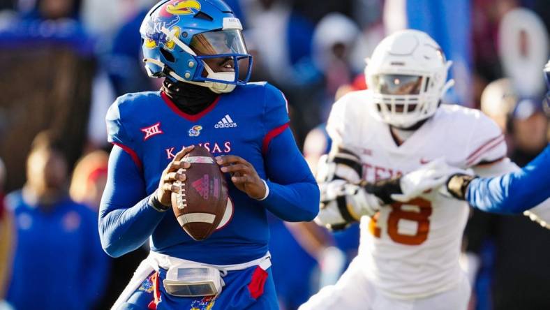 Nov 19, 2022; Lawrence, Kansas, USA; Kansas Jayhawks quarterback Jalon Daniels (6) drops back to pass as Texas Longhorns defensive end Ovie Oghoufo (18) defends during the first half at David Booth Kansas Memorial Stadium. Mandatory Credit: Jay Biggerstaff-USA TODAY Sports