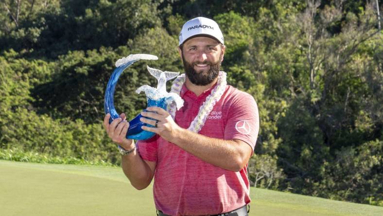 January 8, 2023; Maui, Hawaii, USA; Jon Rahm hoists the trophy on the 18th hole during the final round of the Sentry Tournament of Champions golf tournament at Kapalua Resort - The Plantation Course. Mandatory Credit: Kyle Terada-USA TODAY Sports