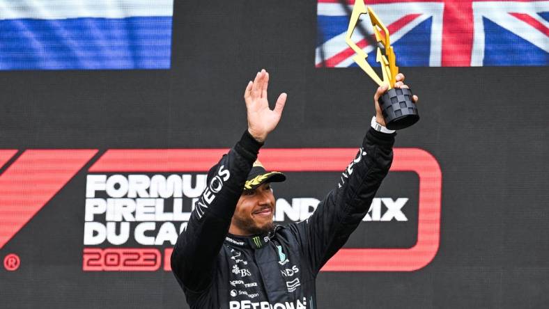 Jun 18, 2023; Montreal, Quebec, CAN; Mercedes driver Lewis Hamilton (GBR) salutes the crowd holding his third place trophy of the Canadian Grand Prix at Circuit Gilles Villeneuve. Mandatory Credit: David Kirouac-USA TODAY Sports