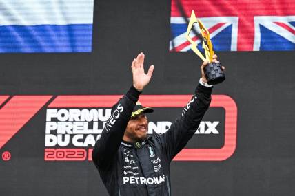 Jun 18, 2023; Montreal, Quebec, CAN; Mercedes driver Lewis Hamilton (GBR) salutes the crowd holding his third place trophy of the Canadian Grand Prix at Circuit Gilles Villeneuve. Mandatory Credit: David Kirouac-USA TODAY Sports