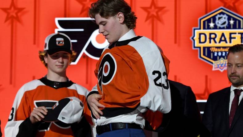 Jun 28, 2023; Nashville, Tennessee, USA; Philadelphia Flyers draft pick Oliver Bonk puts on his sweater after being selected with the twenty second pick in round one of the 2023 NHL Draft at Bridgestone Arena. Mandatory Credit: Christopher Hanewinckel-USA TODAY Sports