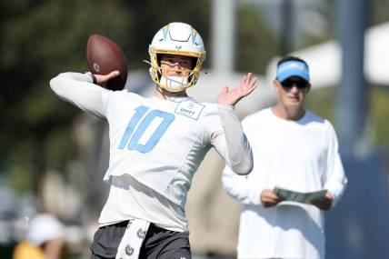 Jul 26, 2023; Costa Mesa, CA, USA; Los Angeles Chargers quarterback Justin Herbert (10) throws the ball as quarterbacks coach Doug Nussmeier watches during training camp at Jack Hammett Sports Complex. Mandatory Credit: Kirby Lee-USA TODAY Sports