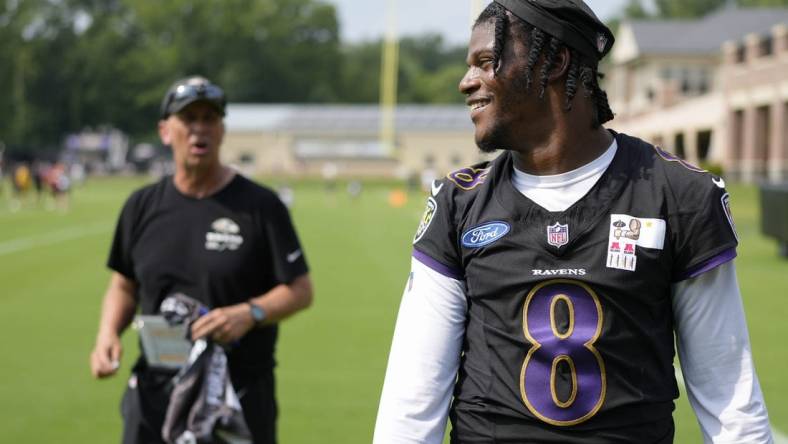 Jul 27, 2023; Owings Mills, MD, USA; Baltimore Ravens quarterback Lamar Jackson (8) smiles at a fan with Baltimore Ravens offensive coordinator Todd Monken standing in the background following training camp practice at Under Armour Performance Center. Mandatory Credit: Brent Skeen-USA TODAY Sports