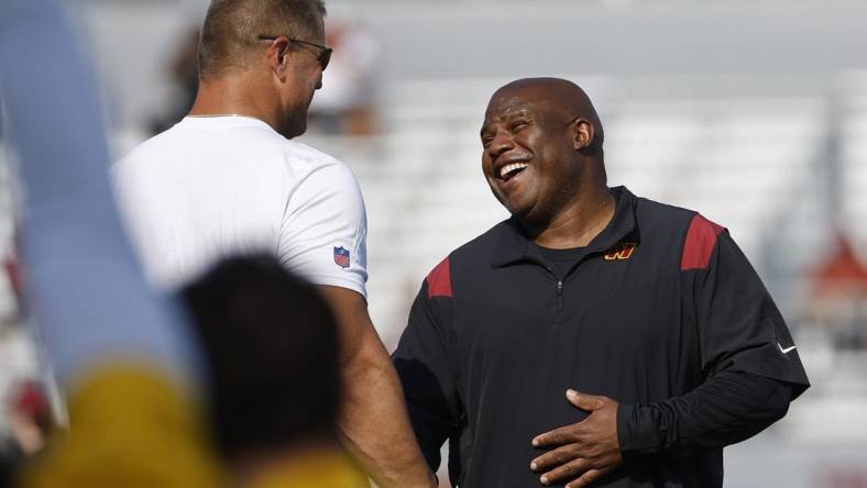 Jul 28, 2023; Ashburn, VA, USA; Washington Commanders assistant head coach/offensive coordinator Eric Bieniemy (R) jokes with Commanders defensive line coach Jeff Zgonina (L) during warmup on day three of Commanders training camp at OrthoVirginia Training Center. Mandatory Credit: Geoff Burke-USA TODAY Sports