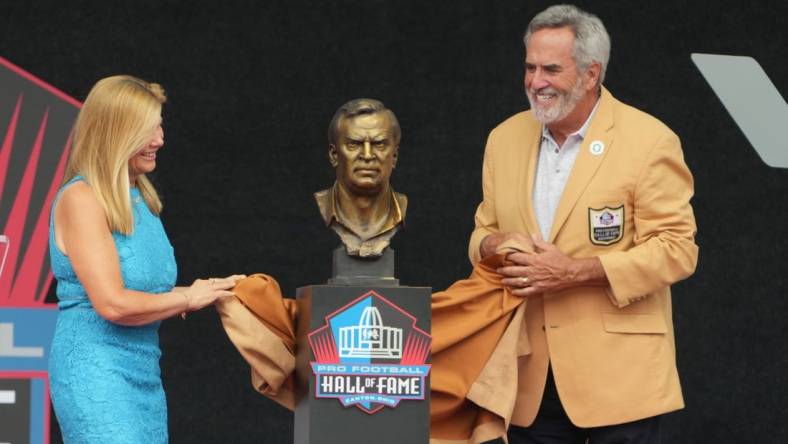 Aug 5, 2023; Canton, OH, USA;   Dan Fouts and Mindy Coryell Lewis unveil the bust of San Diego Chargers and St. Louis Cardinals former coach Don Coryell (deceased) during the 2023 Pro Football Hall of Fame Enshrinement at Tom Benson Hall of Fame Stadium. Mandatory Credit: Kirby Lee-USA TODAY Sports