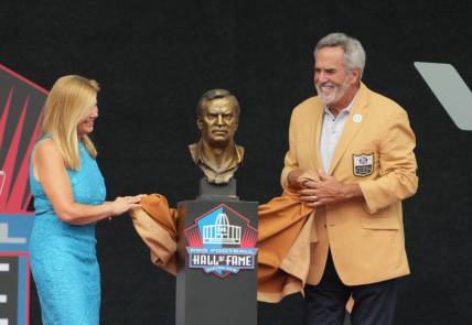 Aug 5, 2023; Canton, OH, USA;   Dan Fouts and Mindy Coryell Lewis unveil the bust of San Diego Chargers and St. Louis Cardinals former coach Don Coryell (deceased) during the 2023 Pro Football Hall of Fame Enshrinement at Tom Benson Hall of Fame Stadium. Mandatory Credit: Kirby Lee-USA TODAY Sports