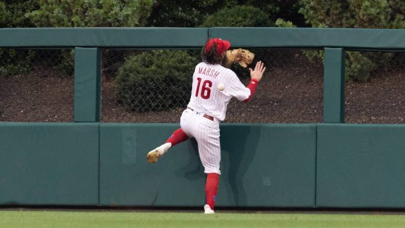 Aug 5, 2023; Philadelphia, Pennsylvania, USA; Philadelphia Phillies center fielder Brandon Marsh (16) is injured while attempting to catch the triple of Kansas City Royals second baseman Samad Taylor (not pictured) during the fifth inning at Citizens Bank Park. Mandatory Credit: Bill Streicher-USA TODAY Sports