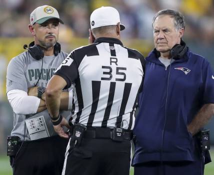 Aug 19, 2023; Green Bay, WI, USA; Green Bay Packers head coach Matt LaFleur and New England Patriots head coach Bill Belichick talk with referee John Hussey (35) during their football game at Lambeau Field. The game was suspended in the fourth quarter following an injury to New England Patriots cornerback Isaiah Bolden (7).  Mandatory Credit: Tork Mason-USA TODAY Sports