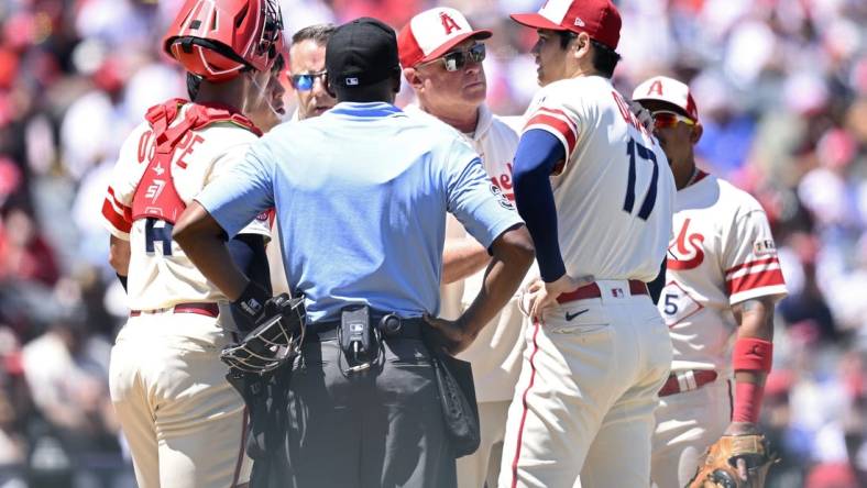 Aug 23, 2023; Anaheim, California, USA; Los Angeles Angels manager Phil Nevin (center) meets with starting pitcher Shohei Ohtani (17) at the mound during the second inning against the Cincinnati Reds at Angel Stadium. Mandatory Credit: Orlando Ramirez-USA TODAY Sports