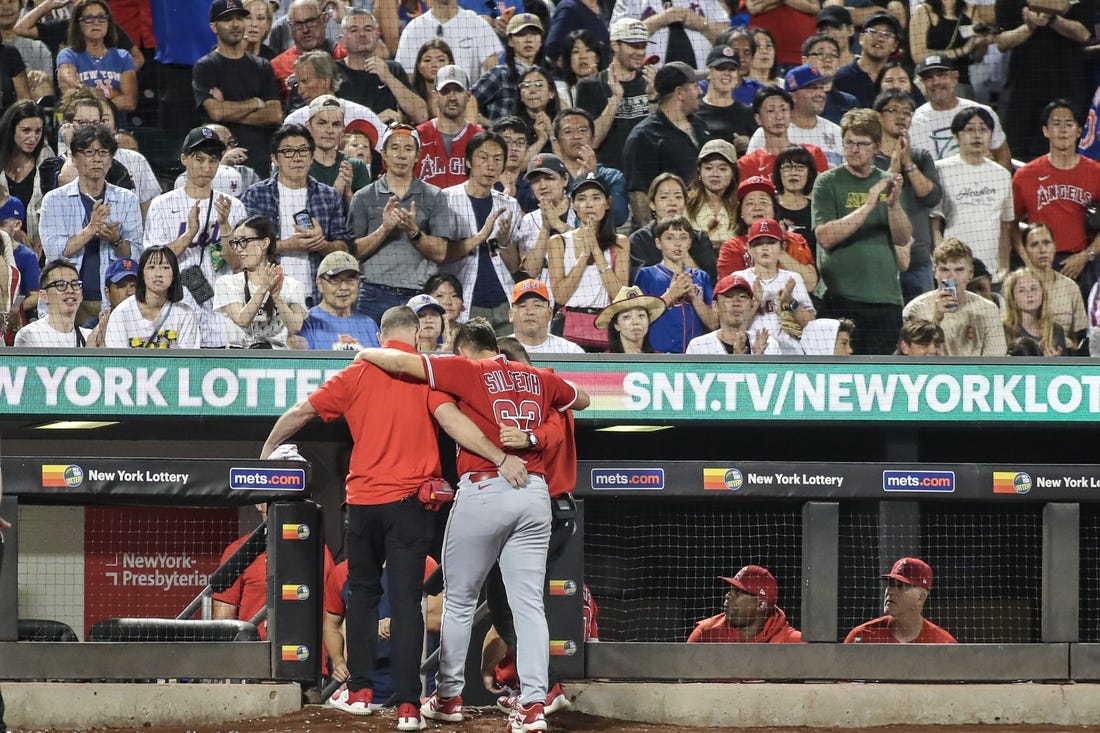 Aug 26, 2023; New York City, New York, USA;  Los Angeles Angels starting pitcher Chase Silseth (63) is helped back into the dugout after getting hit in the head by a throw in the fourth inning against the New York Mets at Citi Field. Mandatory Credit: Wendell Cruz-USA TODAY Sports