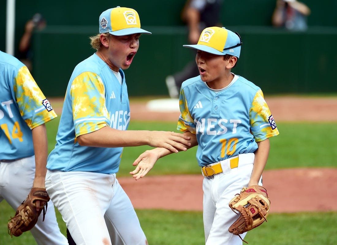 Aug 27, 2023; Williamsport, PA, USA; West Region second baseman Colby Lee (10) is congratulated by first baseman Jaxon Kalish (22) after turning a double play in the second inning against the Caribbean Region at Lamade Stadium. Mandatory Credit: Evan Habeeb-USA TODAY Sports