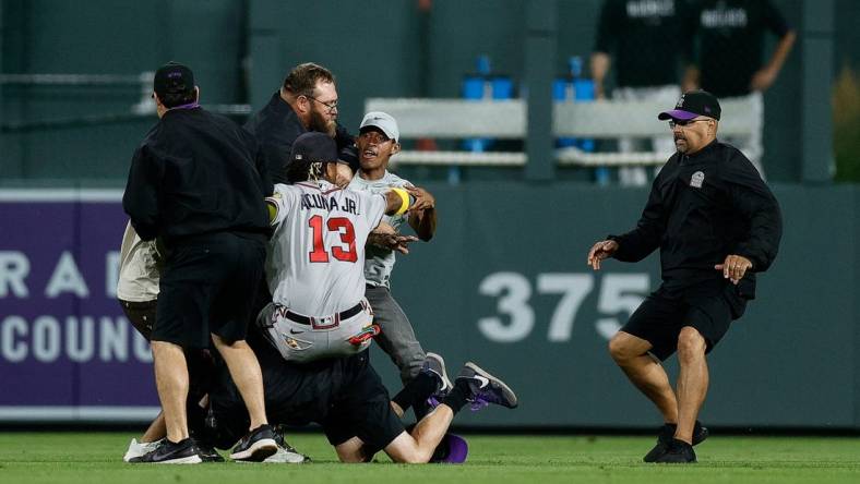 Aug 28, 2023; Denver, Colorado, USA; A fan charges at Atlanta Braves right fielder Ronald Acuna Jr. (13) as grounds crew detains another person in the seventh inning against the Colorado Rockies at Coors Field. Mandatory Credit: Isaiah J. Downing-USA TODAY Sports