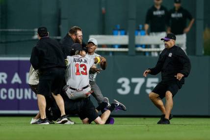 Aug 28, 2023; Denver, Colorado, USA; A fan charges at Atlanta Braves right fielder Ronald Acuna Jr. (13) as grounds crew detains another person in the seventh inning against the Colorado Rockies at Coors Field. Mandatory Credit: Isaiah J. Downing-USA TODAY Sports