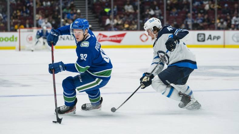 Oct 3, 2021; Vancouver, British Columbia, CAN;  Winnipeg Jets defenseman Declan Chisholm (47) checks Vancouver Canucks forward Vasily Podkolzin (92) in the second period at Rogers Arena. Mandatory Credit: Bob Frid-USA TODAY Sports