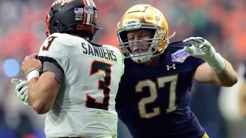 Jan 1, 2022; Glendale, Arizona, USA; Oklahoma State Cowboys quarterback Spencer Sanders (3) eludes the sack of Notre Dame Fighting Irish linebacker JD Bertrand (27) during the first half of the 2022 Fiesta Bowl at State Farm Stadium. Mandatory Credit: Joe Camporeale-USA TODAY Sports