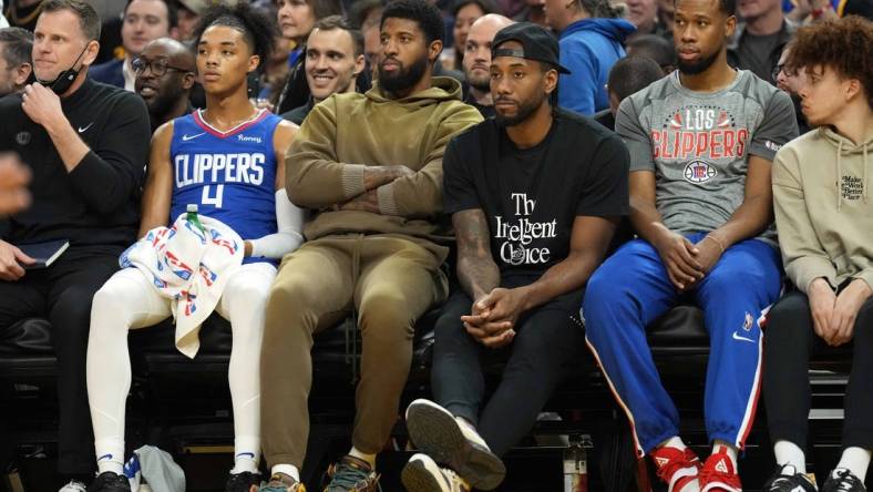 Mar 8, 2022; San Francisco, California, USA; LA Clippers guard Paul George (center, left) and forward Kawhi Leonard (center, right) sit in street clothes on the bench during the second quarter against the Golden State Warriors at Chase Center. Mandatory Credit: Darren Yamashita-USA TODAY Sports