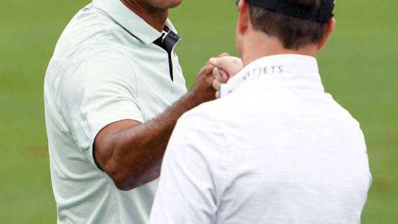 Apr 5, 2022; Augusta, Georgia, USA; Tiger Woods gives Zach Johnson a fist bump on the practice range during a practice round of The Masters golf tournament at Augusta National Golf Club. Mandatory Credit: Danielle Parhizkaran-Augusta Chronicle/USA TODAY Network