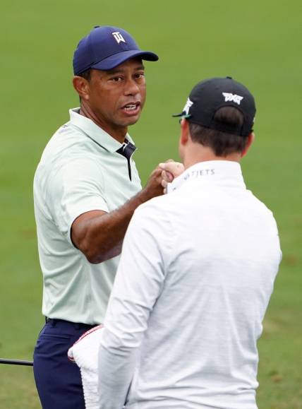 Apr 5, 2022; Augusta, Georgia, USA; Tiger Woods gives Zach Johnson a fist bump on the practice range during a practice round of The Masters golf tournament at Augusta National Golf Club. Mandatory Credit: Danielle Parhizkaran-Augusta Chronicle/USA TODAY Network