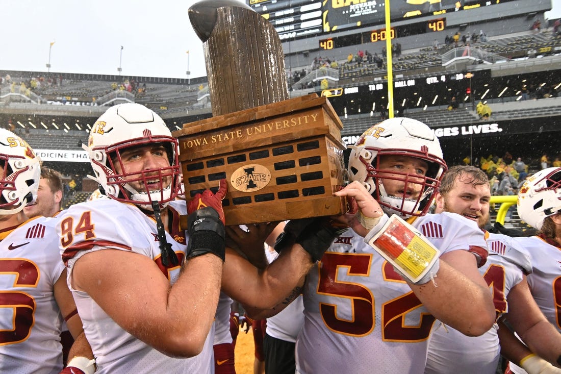 Sep 10, 2022; Iowa City, Iowa, USA; Iowa State Cyclones defensive lineman Kyle Krezek (94) and offensive lineman Trevor Downing (52) carry the Cy-Hawk trophy after the game against the Iowa Hawkeyes at Kinnick Stadium. Mandatory Credit: Jeffrey Becker-USA TODAY Sports