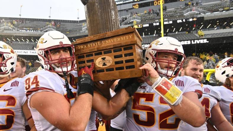 Sep 10, 2022; Iowa City, Iowa, USA; Iowa State Cyclones defensive lineman Kyle Krezek (94) and offensive lineman Trevor Downing (52) carry the Cy-Hawk trophy after the game against the Iowa Hawkeyes at Kinnick Stadium. Mandatory Credit: Jeffrey Becker-USA TODAY Sports