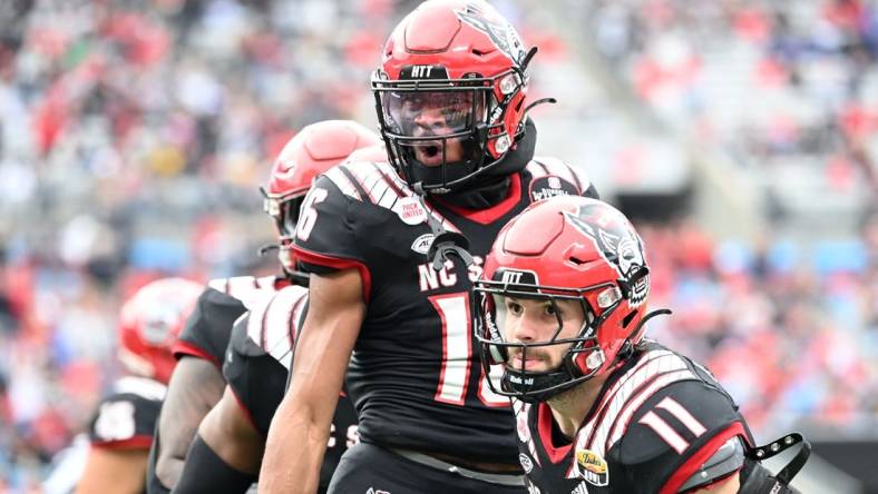 Dec 30, 2022; Charlotte, NC, USA; North Carolina State Wolfpack safety Rakeim Ashford (16) reacts with linebacker Payton Wilson (11) after intercepting the ball in the fourth quarter in the 2022 Duke's Mayo Bowl at Bank of America Stadium. Mandatory Credit: Bob Donnan-USA TODAY Sports