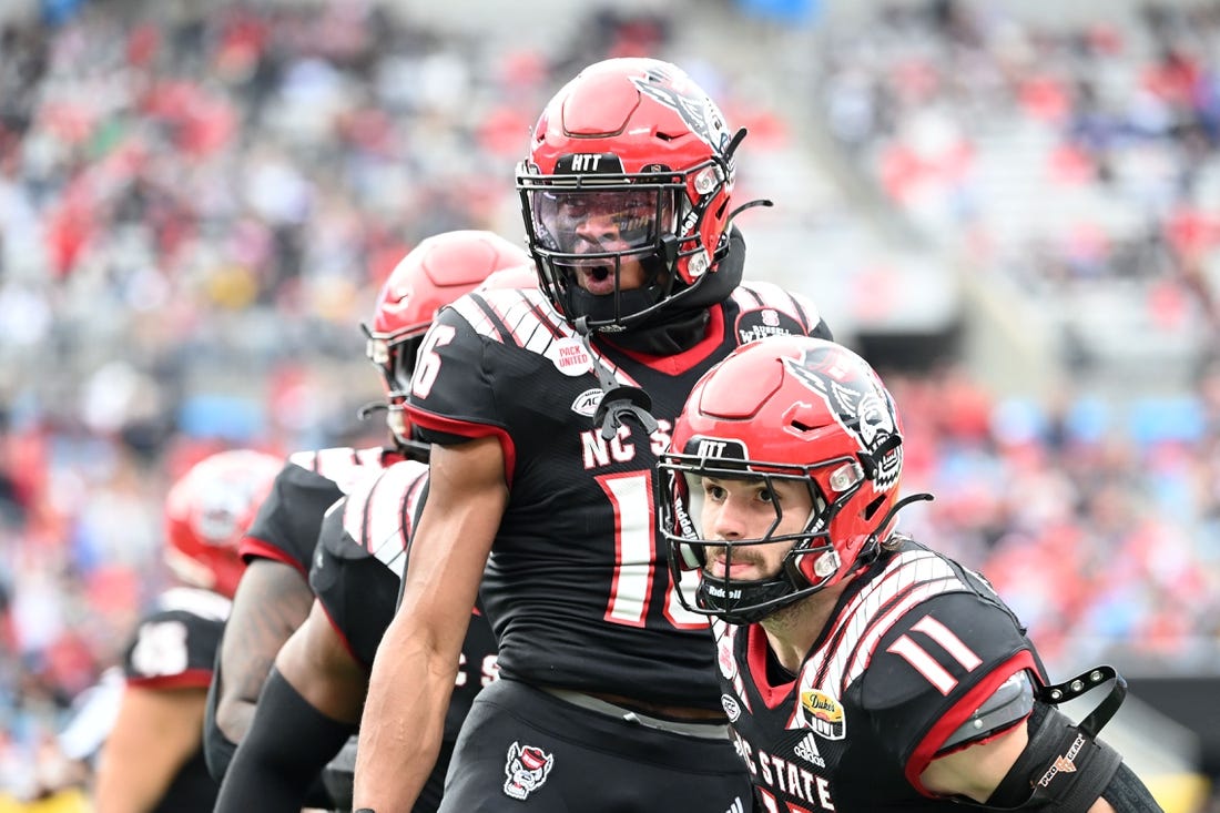 Dec 30, 2022; Charlotte, NC, USA; North Carolina State Wolfpack safety Rakeim Ashford (16) reacts with linebacker Payton Wilson (11) after intercepting the ball in the fourth quarter in the 2022 Duke's Mayo Bowl at Bank of America Stadium. Mandatory Credit: Bob Donnan-USA TODAY Sports