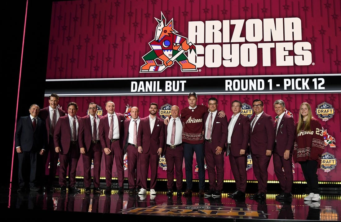 Jun 28, 2023; Nashville, Tennessee, USA; Arizona Coyotes draft pick Daniil But stands with Coyotes staff after being selected with the twelfth pick in round one of the 2023 NHL Draft at Bridgestone Arena. Mandatory Credit: Christopher Hanewinckel-USA TODAY Sports