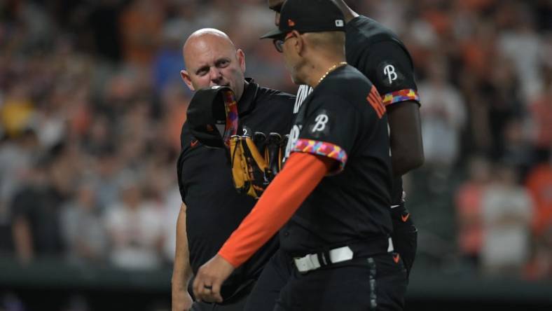 Aug 25, 2023; Baltimore, Maryland, USA; Baltimore Orioles relief pitcher Felix Bautista (74) walks off the field with major league coach Jos  Hern ndez (59) and team trainer during the ninth inning against the Colorado Rockies  at Oriole Park at Camden Yards. Mandatory Credit: Tommy Gilligan-USA TODAY Sports