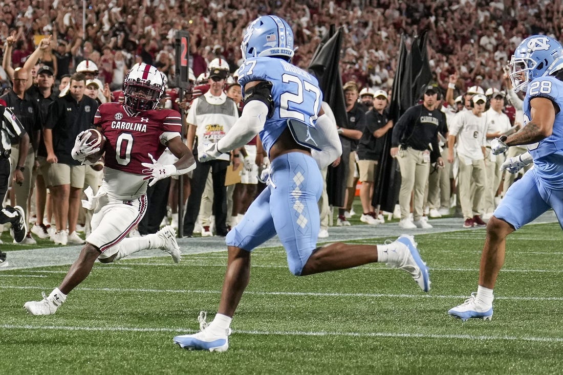 Sep 2, 2023; Charlotte, North Carolina, USA; South Carolina Gamecocks running back Juju McDowell (0) runs towards the end zone chased by North Carolina Tar Heels defensive back Giovanni Biggers (27) during the second quarter at Bank of America Stadium. Mandatory Credit: Jim Dedmon-USA TODAY Sports