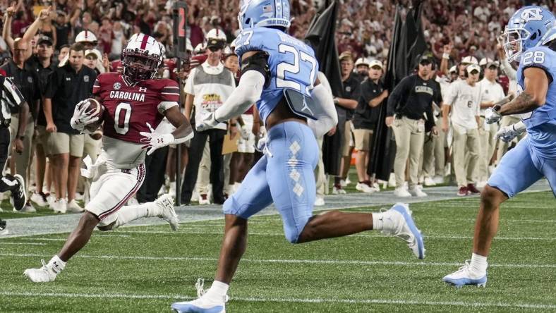 Sep 2, 2023; Charlotte, North Carolina, USA; South Carolina Gamecocks running back Juju McDowell (0) runs towards the end zone chased by North Carolina Tar Heels defensive back Giovanni Biggers (27) during the second quarter at Bank of America Stadium. Mandatory Credit: Jim Dedmon-USA TODAY Sports