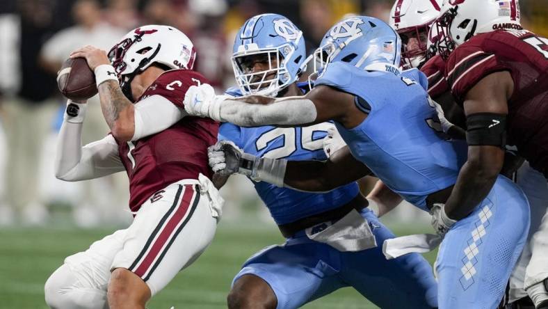 Sep 2, 2023; Charlotte, North Carolina, USA; North Carolina Tar Heels linebacker Kaimon Rucker (25) and linebacker Amari Gainer (3) tackle South Carolina Gamecocks quarterback Spencer Rattler (7) during the second half at Bank of America Stadium. Mandatory Credit: Jim Dedmon-USA TODAY Sports