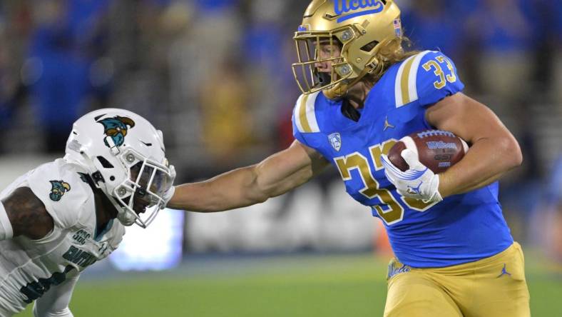 Sep 2, 2023; Pasadena, California, USA;  UCLA Bruins running back Carson Steele (33) pushes off Coastal Carolina Chanticleers safety Tobias Fletcher (4) for a first down in the first half at Rose Bowl. Mandatory Credit: Jayne Kamin-Oncea-USA TODAY Sports