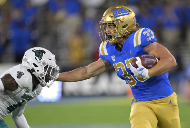 Sep 2, 2023; Pasadena, California, USA;  UCLA Bruins running back Carson Steele (33) pushes off Coastal Carolina Chanticleers safety Tobias Fletcher (4) for a first down in the first half at Rose Bowl. Mandatory Credit: Jayne Kamin-Oncea-USA TODAY Sports